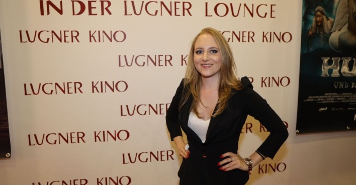 Jacqueline „Jacky“ Lugner posiert vor einer Fotowand des Lugner Kinos in Wien. Die Geschäftsführerin der Lugner City feiert einen historischen Umsatzrekord.