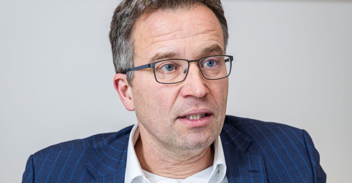 Porträt von AMS-Chef Johannes Kopf mit Brille, blauem Sakko und weißem Hemd. Er fordert ein höheres Pensionsantrittsalter in Österreich.