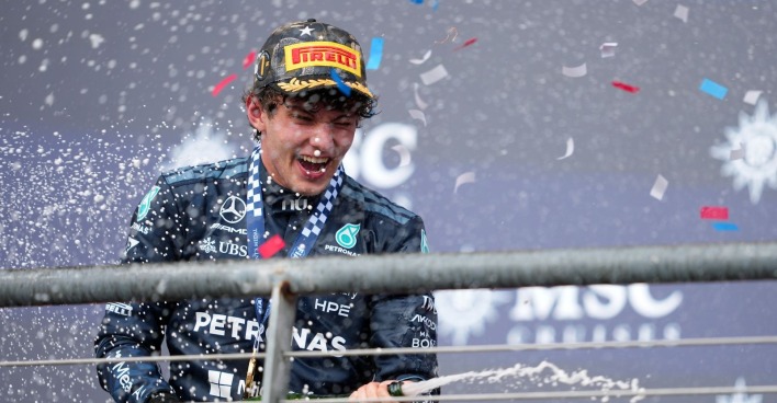 Mercedes-Pilot Andrea Kimi Antonelli jubelt auf dem Siegerpodest mit Pirelli-Kappe und Medaille, während Champagner spritzt und Konfetti fällt.