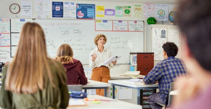 Lehrerin steht in einer Klasse und unterrichtet