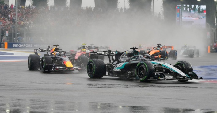 Mercedes und Red Bull beim Formel-1-Sprint in Singapur auf regennasser Rennstrecke mit starker Gischt.