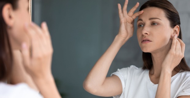 Frau sucht ihr Spiegelbild nach Falten ab