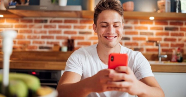 Junger Mann lacht über Smartphone-Witz | Credit: iStock.com/Pascal Skwara