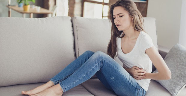 Frau mit Bauchschmerzen auf Sofa