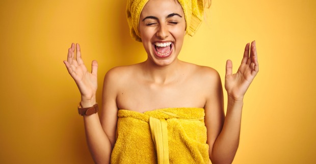 Eine lachende junge Frau mit Badehandtuch und Handtuchturban
