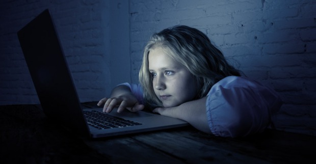 Kind starrt gebannt auf den Bildschirm eines Laptops
