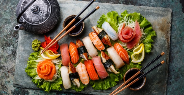 Eine Sushiplatte mit Essstäbchen, Schalen für die Sojasauce und einem Teekessel