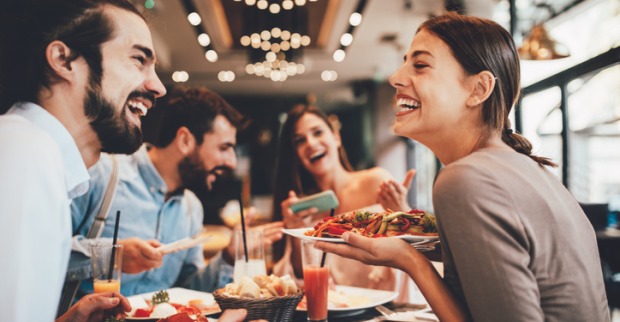 Lachende Gesicheter rund um den Restaurant-Tisch