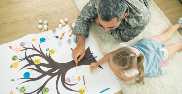 Vater und Tochter am Boden liegend und einen Stammbaum malend