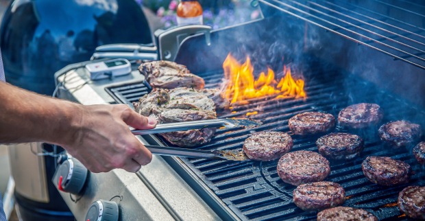 Nahaufnahme eines rauchenden Grills, auf den unterschiedliche Fleischsorten gelegt wurden