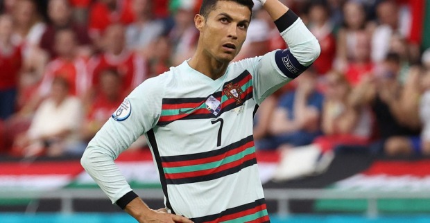 Cristiano Ronaldo im Dress der portugiesischen Nationalmannschaft hat eine Hand in die Hüfte gestemmt und greift sich mit der anderen fragend auf den Kopf.
