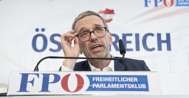 Herbert Kickl auf einer Pressekonferenz im Portrait. Hinter ihm der Schriftzug "Österreich". Unter seinem Mikrofon ein Aufsteller mit dem Logo der FPÖ und dem Text: "Freiheitlicher Parlamentsklub"