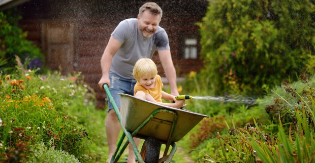 Mann schiebt Kind in Scheibtruhe | Credit: iStock.com/SbytovaMN