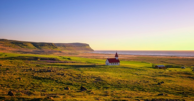 Einsame isländische Landschaft mit Kirche im Licht der untergehenden Sonne | Credit: iStock.com/miroslav_1