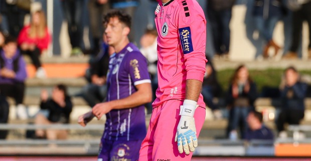 Der Torhüter des SK Austria Klagenfurt, Phillip Menzel, in einer rosaroten Torhütermontur auf dem Spielfeld vor der Zuschauertribüne