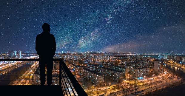 Mann betrachtet vom Balkon aus den nächtlichen Sternenhimmel | Credit: iStock.com/Artem Peretiatko