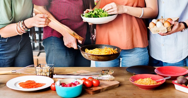 Junge Menschen beim gemeinsamen Essen im Stehen | Credit: iStock.com/Rawpixel