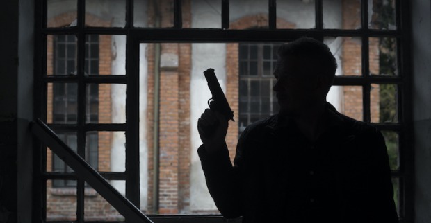 Mann mit Pistole am Fenster