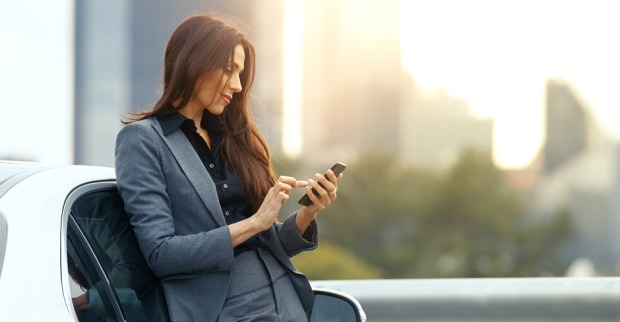 Frau checkt ihr Smartphone vor der Fahrt | Credit: iStock.com/gorodenkoff