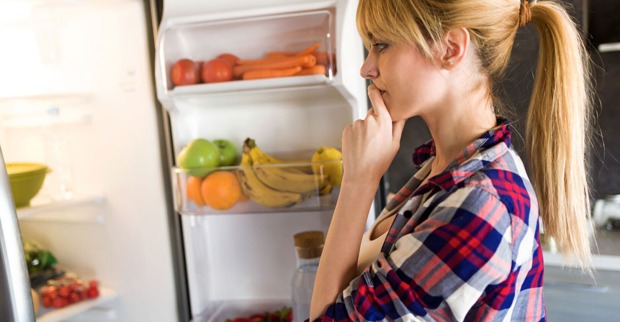 Eine junge Frau steht vor dem geöffneten Kühlschrank | Credit: iStock.com/nensuria