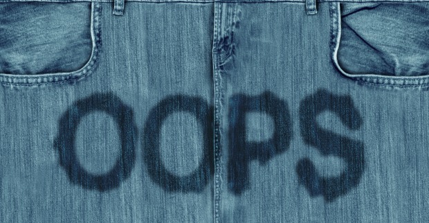 Nahaufnahme einer Jeans mit feuchtem Oops-Schriftzug im Schritt