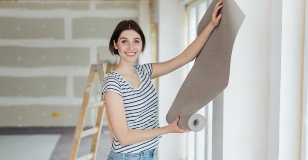 Frau hält eine Tapetenrolle in der Hand | Credit: iStock.com/stockfour