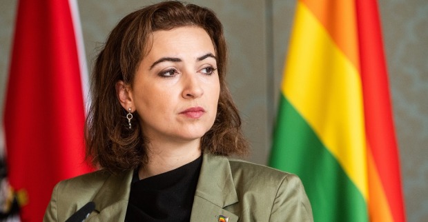 Alma Zadic vor der österreichischen und der Regenbohnenfahne.