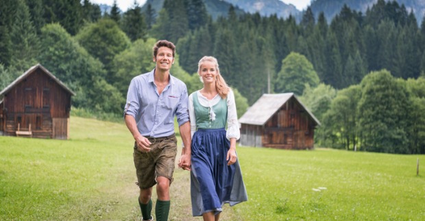 Paar in Dirndl und Lederhose auf grüner Wiese