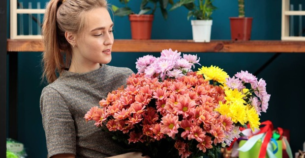 Junge Frau mit Chrysanthemen in der Hand | Credit: iStock.com/Svyatoslav Balan