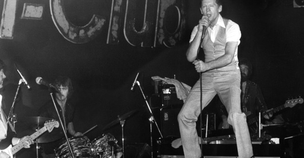 Rock‘n‘Roll-Legende Jerry Lee Lewis auf einem Klavier stehend