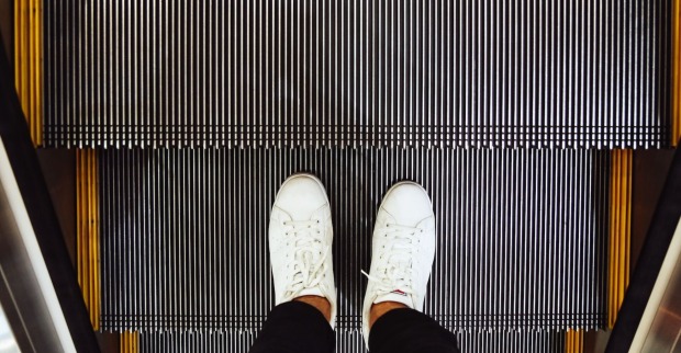 Mann mit weißen Schuhen auf einer Rolltreppe | Credit: iStock.com/toncd32