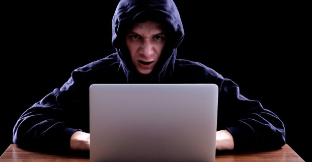 Mann mit schwarzem Kapuzenpullover vor einem Laptop| Credit: iStock.com/filistimlyanin