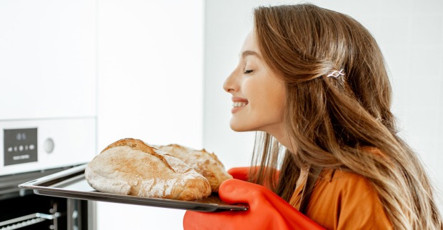 Glückliche Frau erfreut sich an frisch gebackenem Brot | Credit: iStock.com/RossHelen