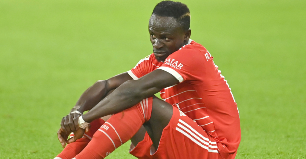 Sadio Mané, der im Dress des FC Bayern München mit einem nachdenklichen Gesichtsausdruck auf dem Spielfeld sitzt.