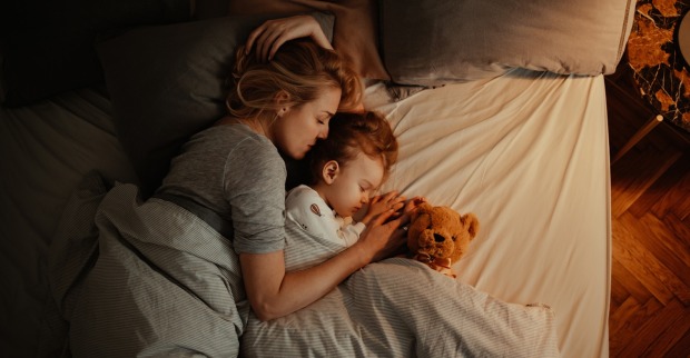 Frau schläft mit Kinder im Bett. | Credit: iStock.com/miniseries