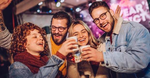 Freunde stoßen an einem Stand mit Glühwein an | Credit: iStock.com/Mina3686
