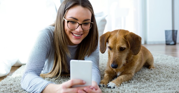 Frau liegt mit Hund und Smartphone am Boden | Credit: iStock.com/nensuria