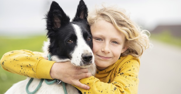 Blondes Kind umarmt Hund