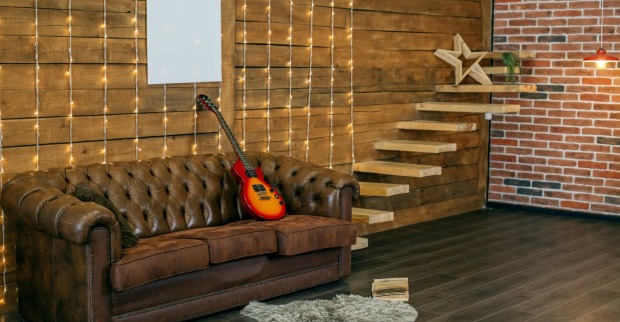 Eine Gitarre liegt auf einem Kunstledersofa | Credit: iStock.com/Olha Romaniuk