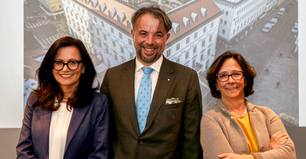 Die Vorstände der Kärntner Sparkasse vor einem auf die Rückwand projezierten Bild der Firmenzentrale