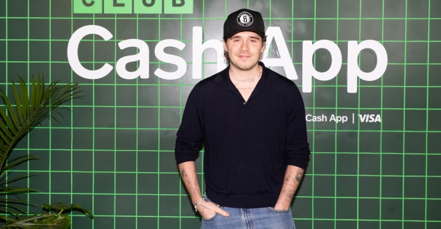 Brooklyn Beckham mit schwarzem Sweater und schwarzem Baseball-Cap.