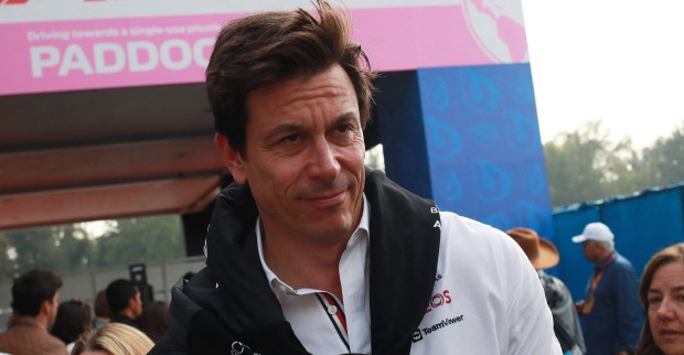 Toto Wolff in Großaufnahme am Rande der Rennstrecke. Er trägt ein weißes Hemd, über den Schultern hängt vor der Brust verknotet ein schwarzer Sweater.
