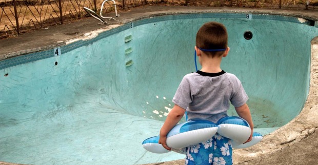 Kind steht vor leerem Schwimmbecken