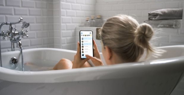 Frau liegt mit Handy in der Badewanne