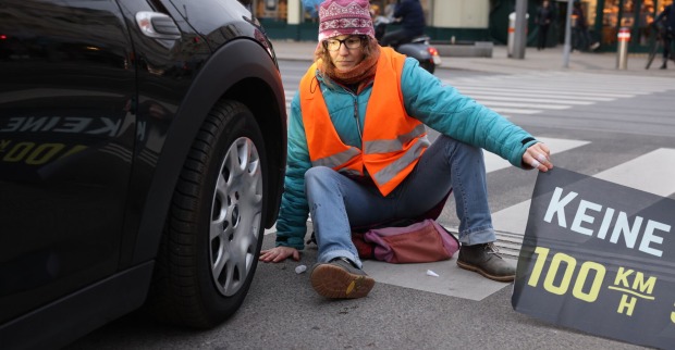 Eine Klima-Kleberin sitzt direkt vor einem Auto. (SYMBOLBILD)