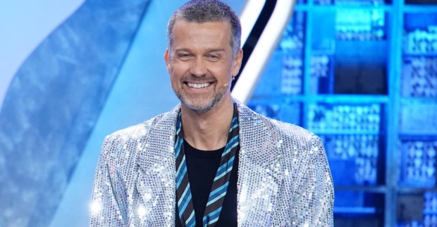 Ein Mann mit einem Glitzersakko und einer Krawatte ganz lässig umgebunden