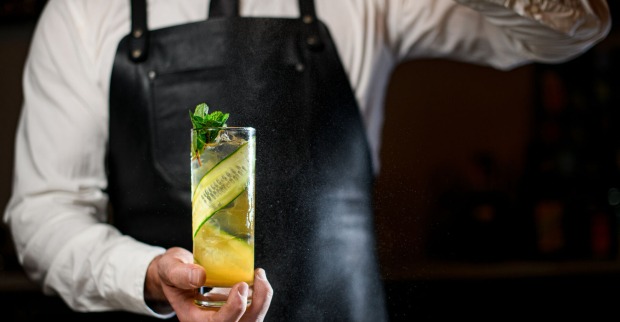 Barkeeper hält einen Cocktail mit einer langen Gurkenscheibe | Credit: istock.com/MaximFesenko