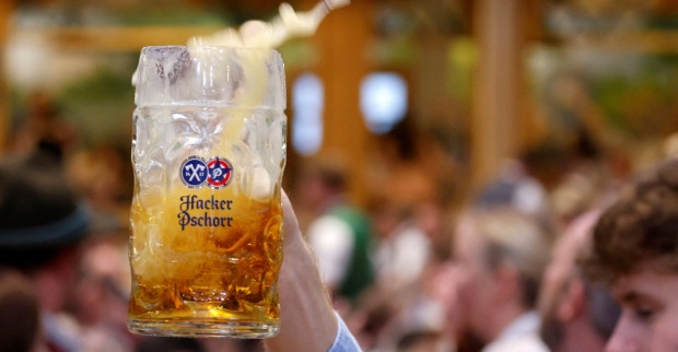 Jemand hält eine Maß Bier in einem Festzelt in die Höhe.