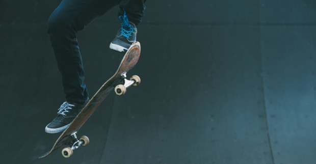Zwei Füße und ein Skateboard in der Luft.