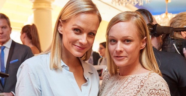 Zwei junge Frauen mit blonden Haaren lachen in die Kamera.